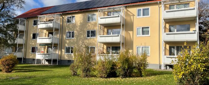 Ein modernisiertes Objekt, Fassade saniert und gelb gestrichen, neues Dach mit PV-Anlage, weiße Balkone